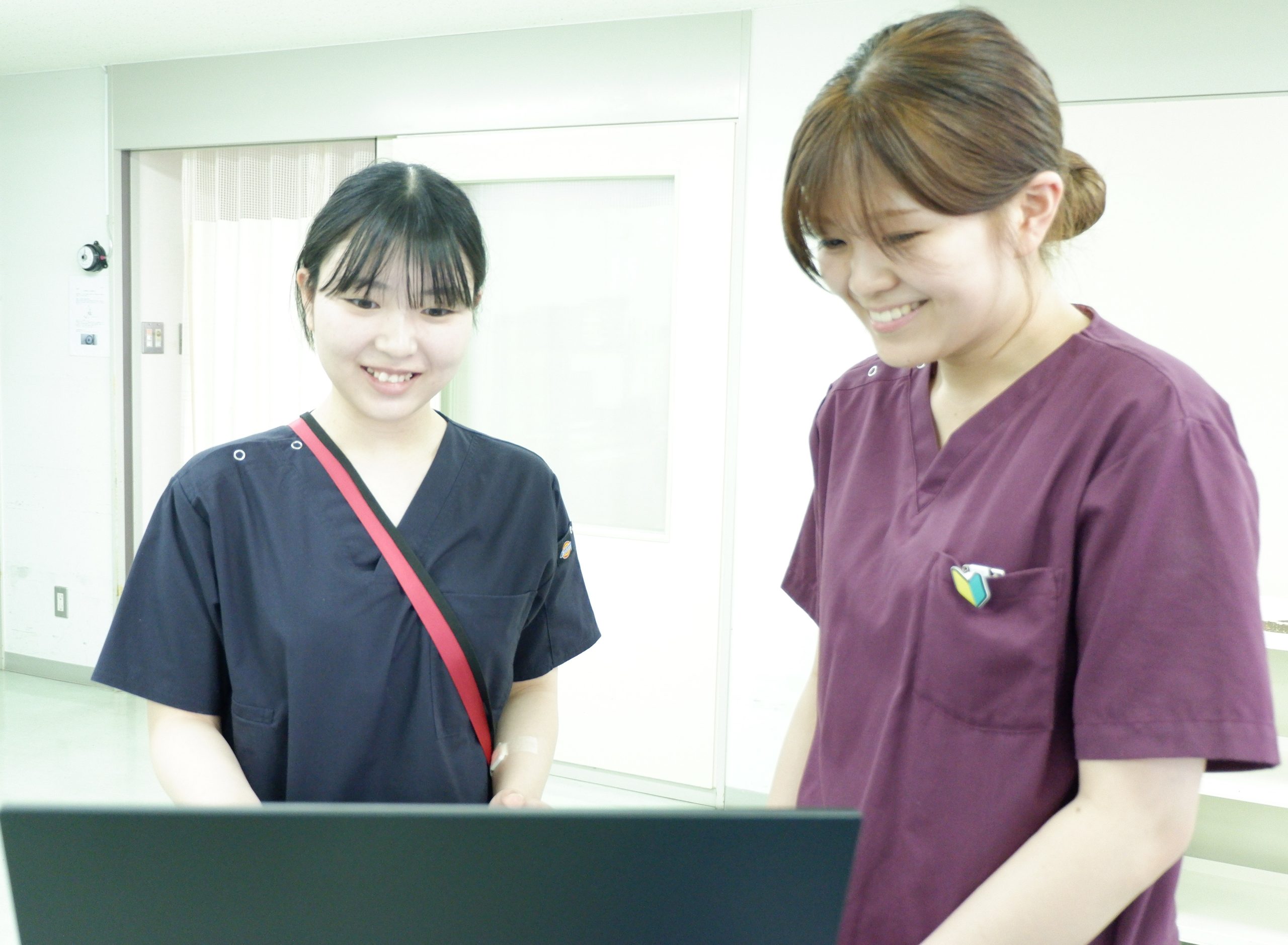 先輩看護師と新人看護師が一緒に画面を見ながら笑顔で確認する様子